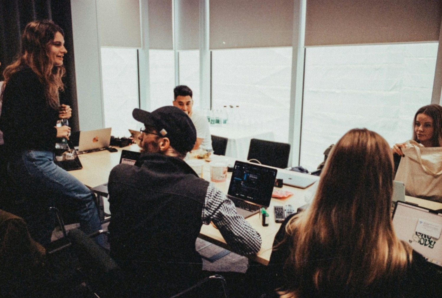 Eine Gruppe von Menschen sitzt mit Laptops um einen Tisch.
